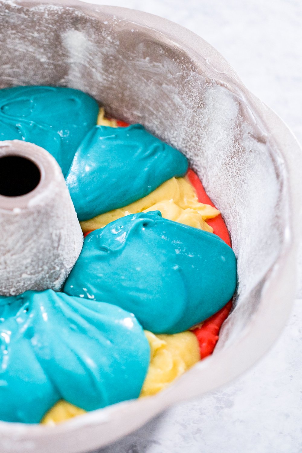 Whip up this festive 4th of July Bundt Cake in no time with just cake mix, food coloring, and canned frosting. The perfect patriotic dessert!